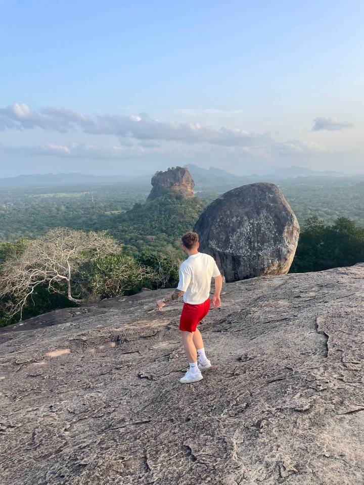 Personne marchant sur une surface rocheuse avec vue sur Sigiriya.
