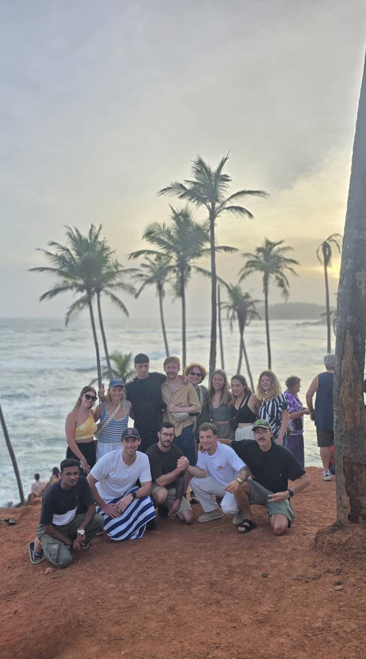 Photo de groupe avec des personnes qui posent près de palmiers et de l'océan.