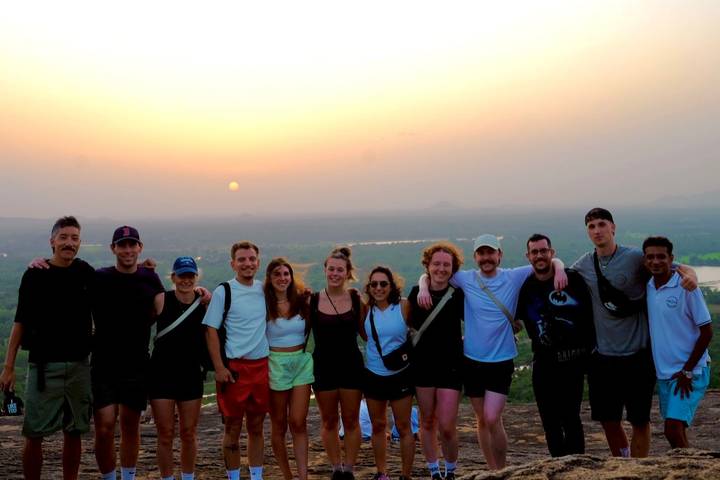 Un groupe de personnes posant pour une photo avec un coucher de soleil pittoresque en arrière-plan.