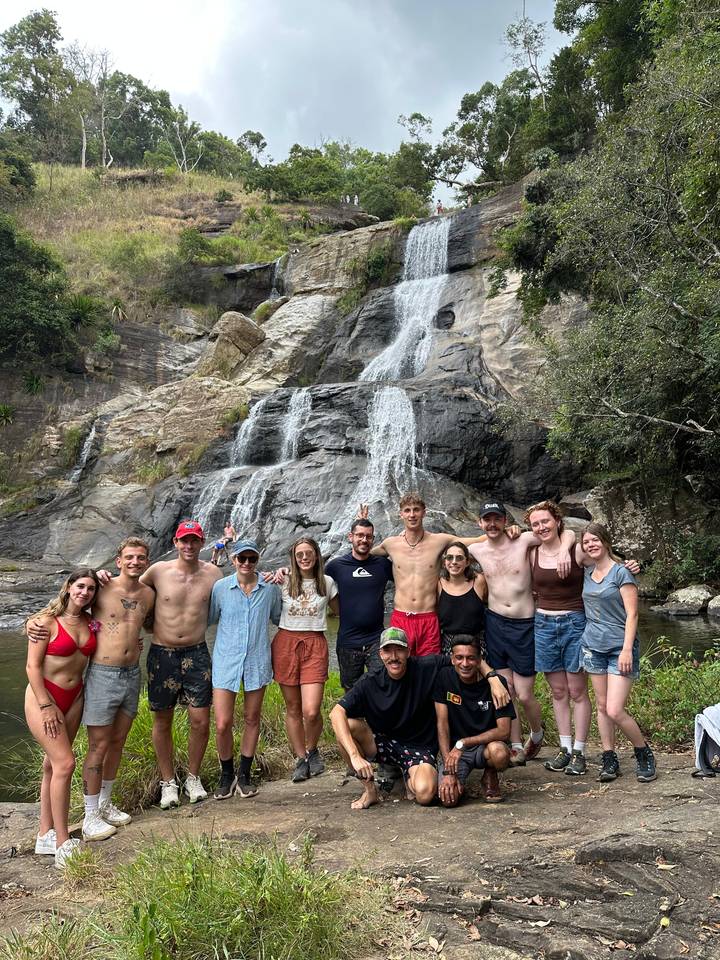 Groupe de personnes debout devant une cascade.