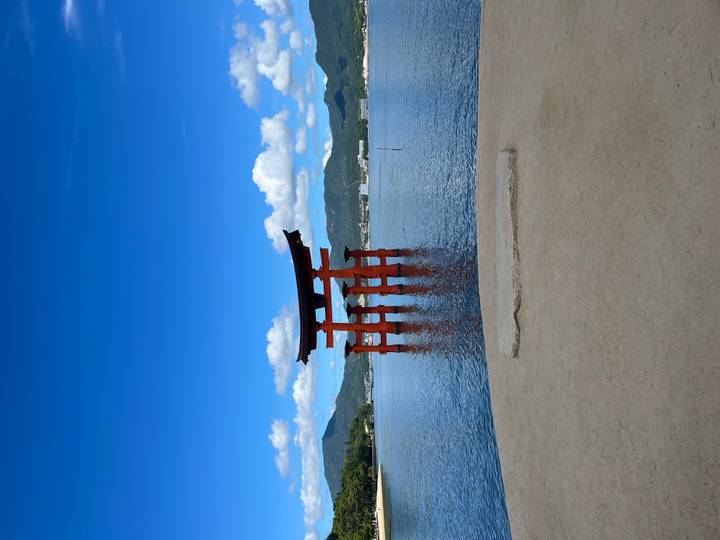 Porte torii emblématique dans l'eau sous un ciel bleu.