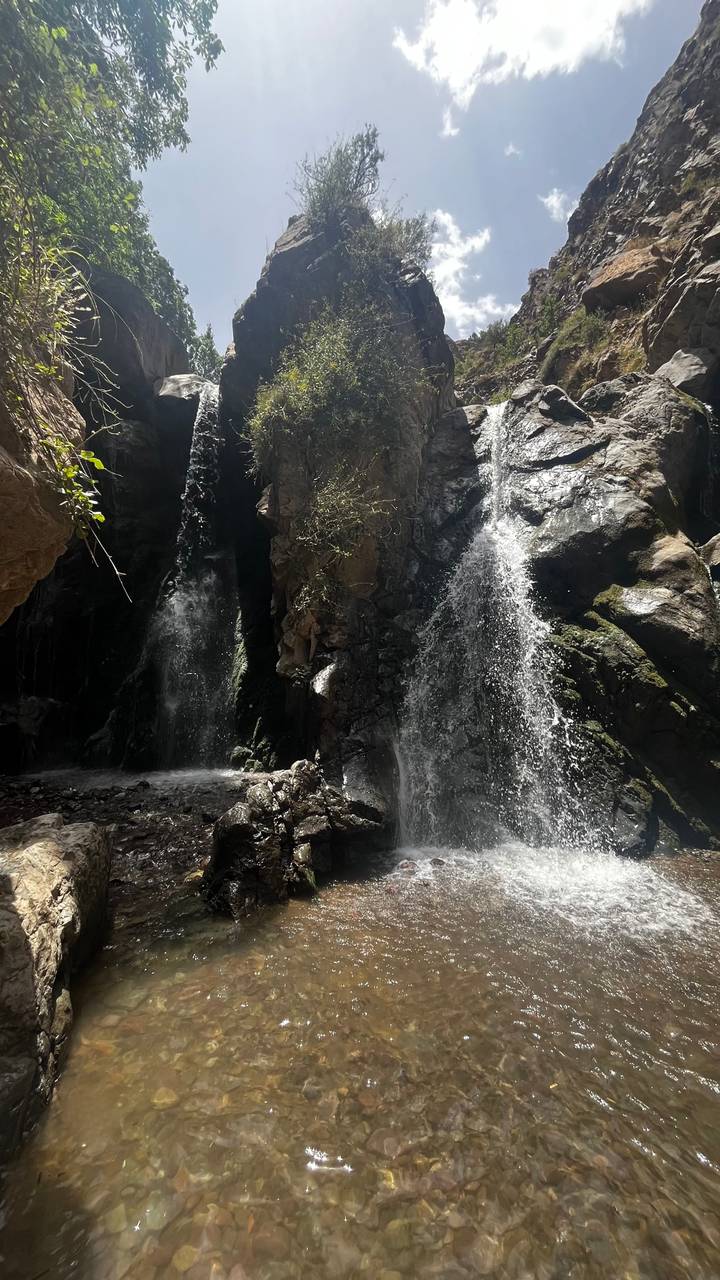 Wasserfälle, die über Felsen in einem schattigen Bereich herabstürzen.