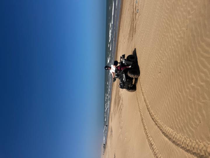 Person, die auf einem ATV an einem sandigen Strand fährt.