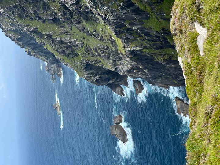 Steep cliffs by the ocean with waves crashing.