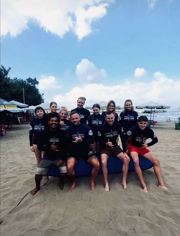 Groupe de surfeurs posant avec des planches de surf sur la plage