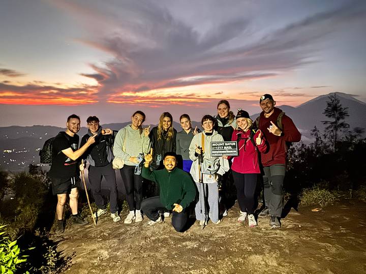 Groupe de randonneurs posant au sommet avec un lever de soleil en arrière-plan