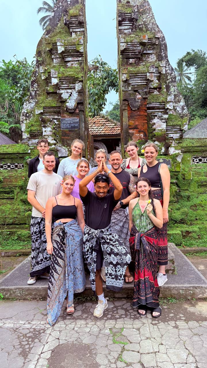 Photo de groupe de personnes devant un temple ancien couvert de mousse.