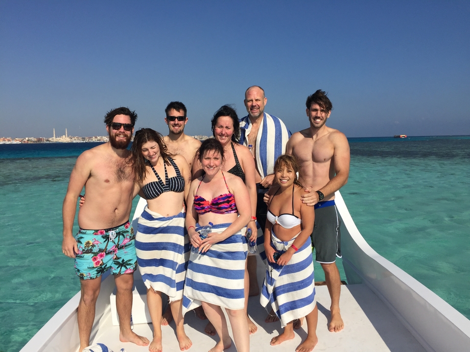 Group of people on a boat near clear blue water.
