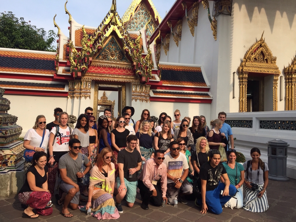 A large group of people posing in front of a temple with ornate decorations.