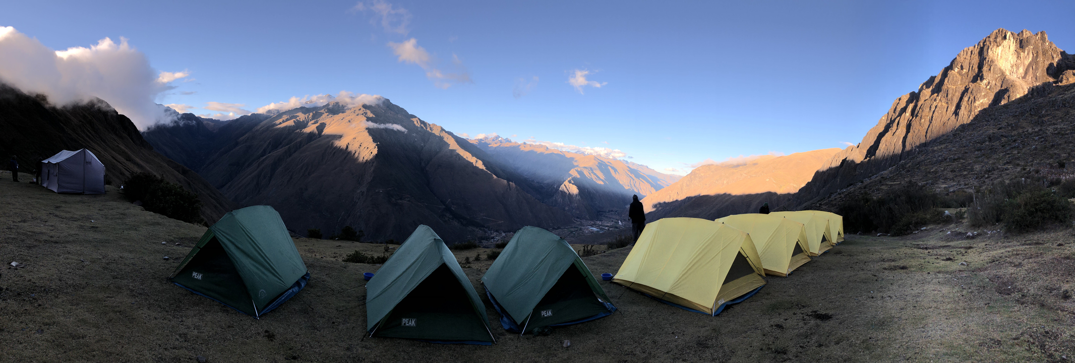 Tentes installées le long d'une vallée montagneuse.