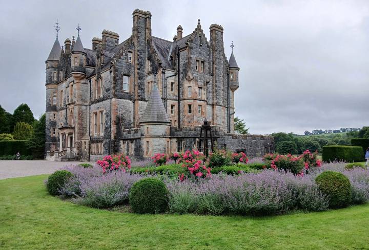 Beautifully landscaped garden in front of a Victorian-style castle.