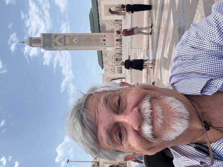 Man taking a selfie in front of a large mosque.