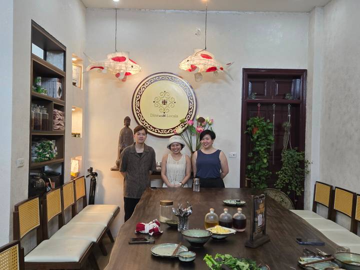 Trois personnes posent dans un espace de cours de cuisine vietnamienne.