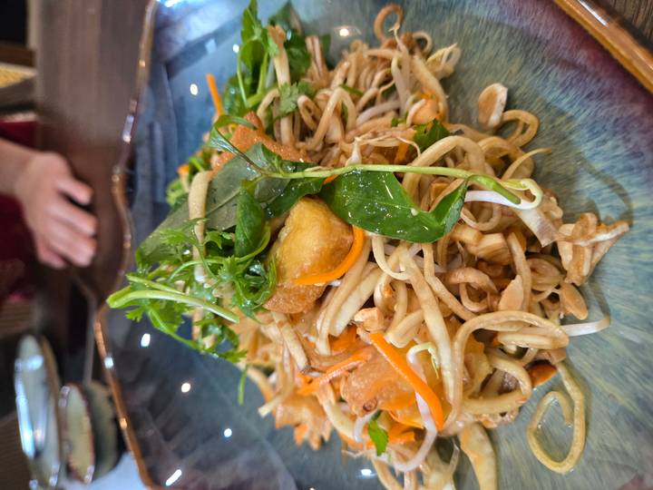 Un plat de nouilles, d'herbes et de légumes dressé de manière attrayante.