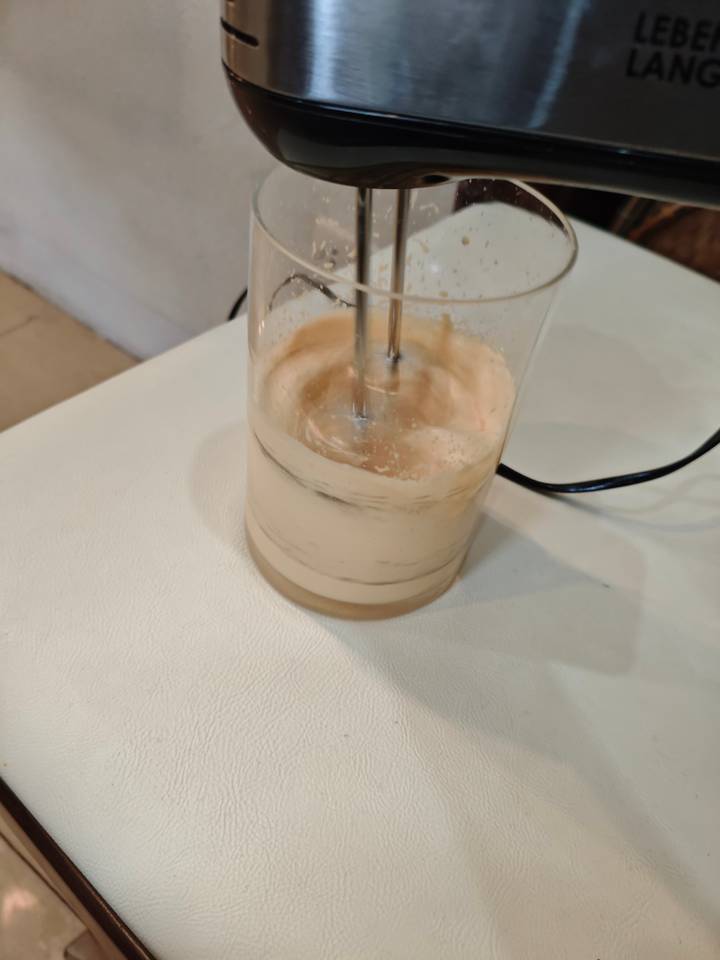 Un récipient en verre contenant un liquide beige en train d'être remué.