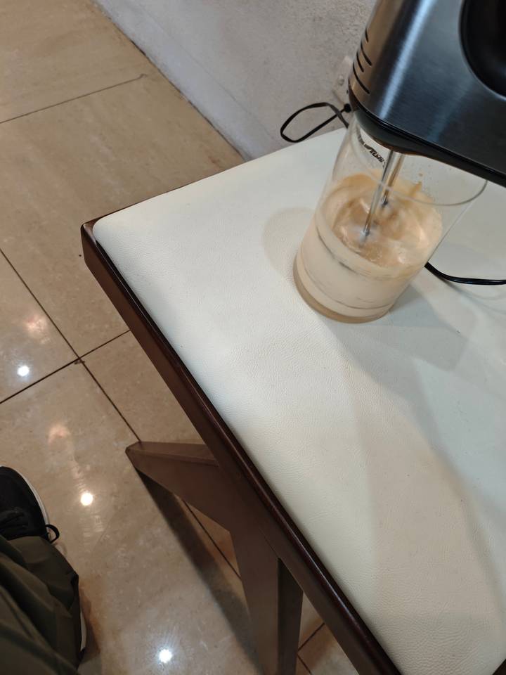 Gros plan d'un mélangeur dans un verre avec un liquide crémeux.