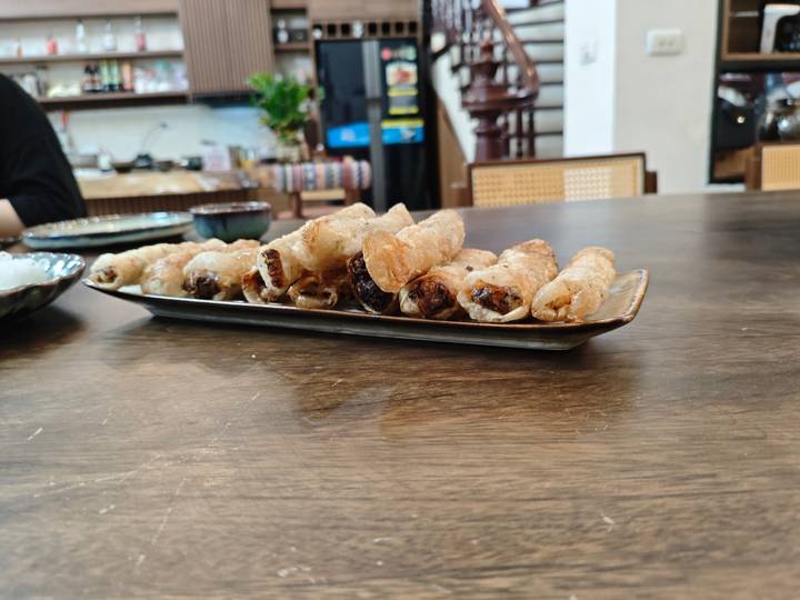 Assiette de rouleaux de printemps dorés frits sur une table.