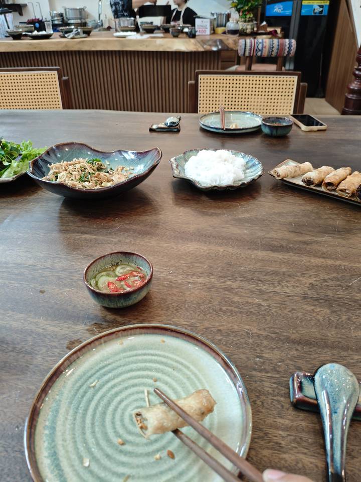 Des plats avec des nouilles, des rouleaux et de la sauce sur une table.
