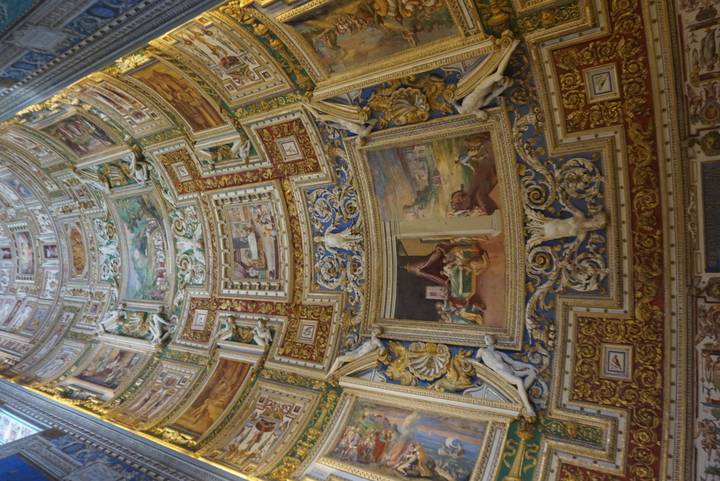 Intricate ceiling of a historic building with detailed frescoes.