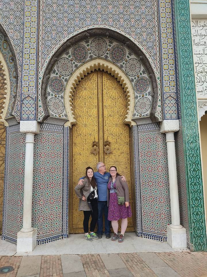 Famille posant devant une grande porte dorée avec des carreaux.