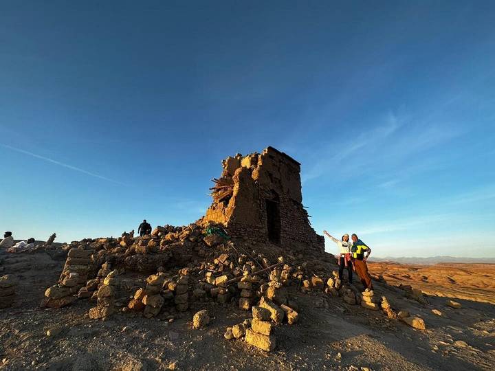 Des gens pointant du doigt une ruine antique au coucher du soleil.