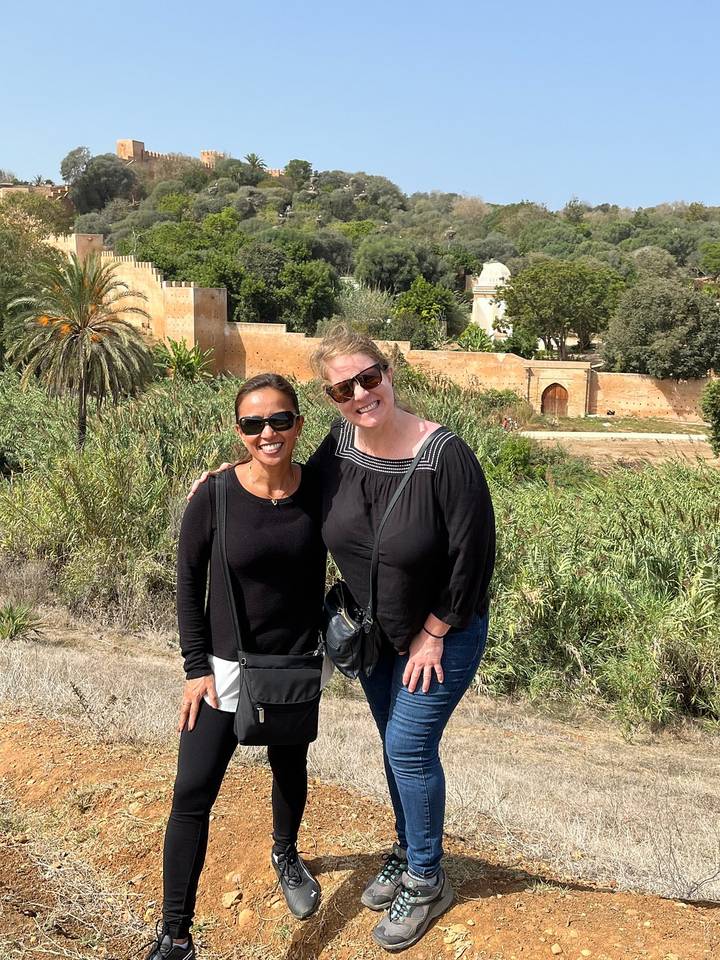 Deux femmes posant avec un mur historique en arrière-plan.