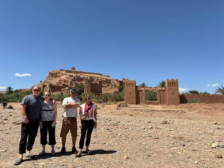 Des gens debout devant Aït-ben-Haddou contre un ciel dégagé.