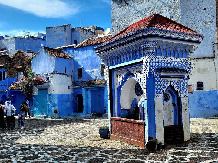 Architecture bleue et blanche sur une place de ville marocaine.