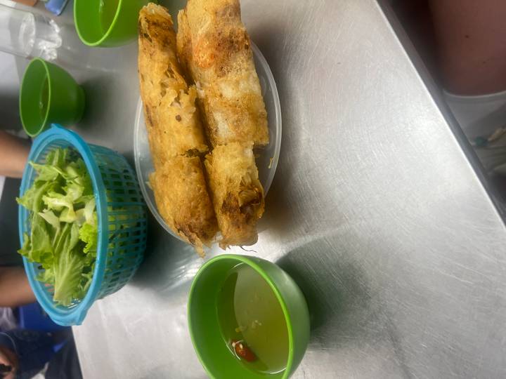 Assiette de rouleaux de printemps frits et sauce d'accompagnement sur une table en métal.