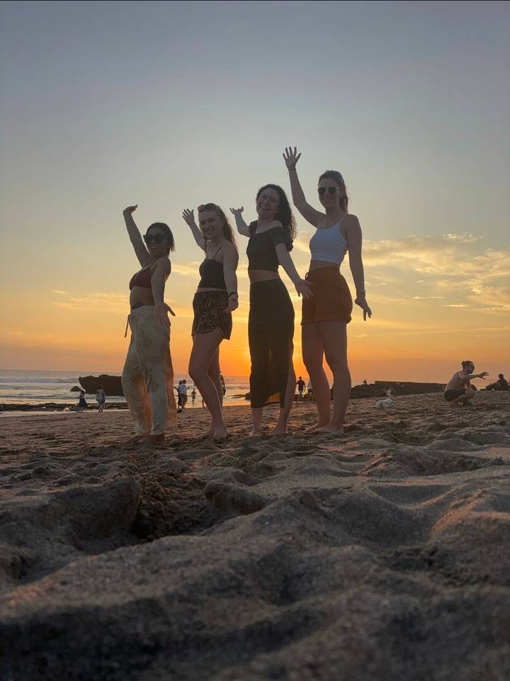 Quatre femmes posant sur une plage au coucher du soleil.