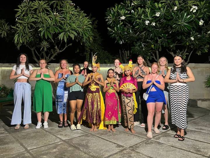 Un groupe de personnes posant avec des danseurs locaux en tenue traditionnelle balinaise.