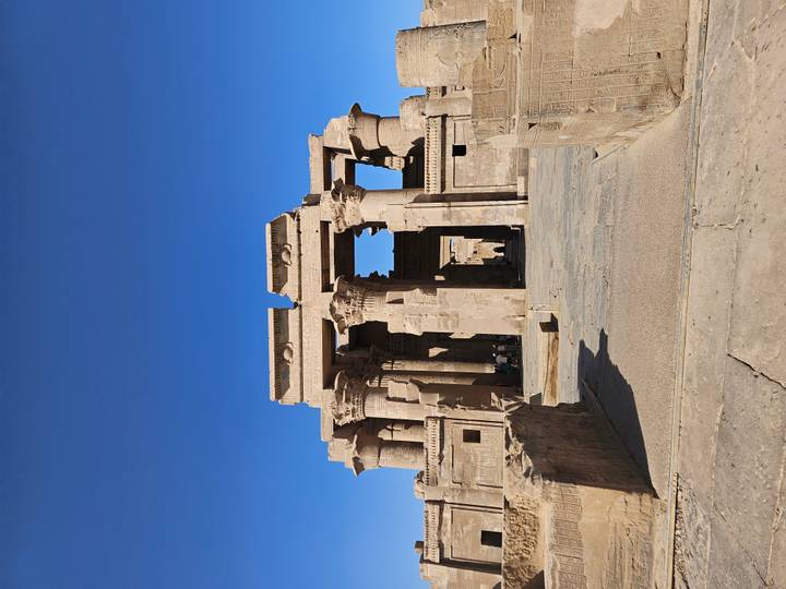 Temple égyptien antique sous un ciel bleu éclatant.