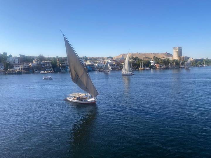 Voiliers sur le fleuve Nil avec une ville en arrière-plan.