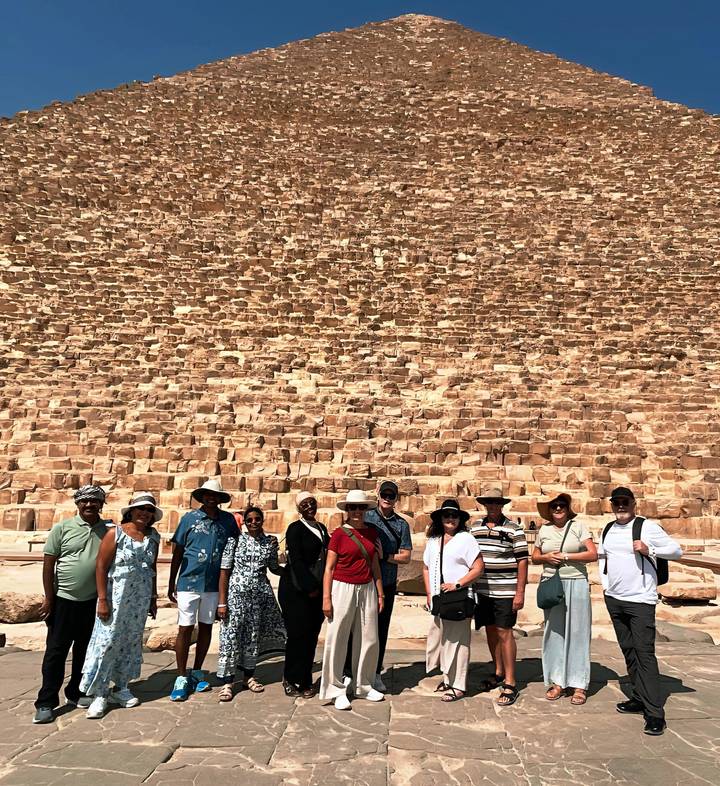 Groupe de touristes posant devant une pyramide.