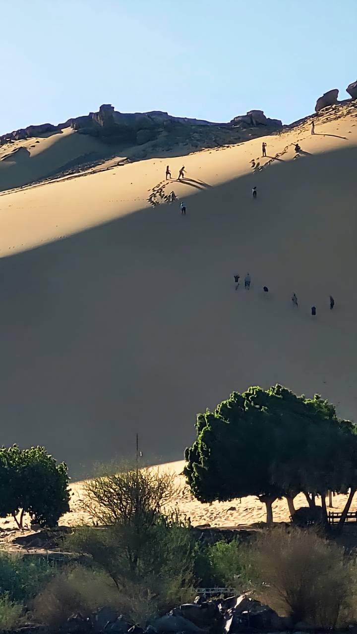 Des gens qui marchent sur des dunes de sable.