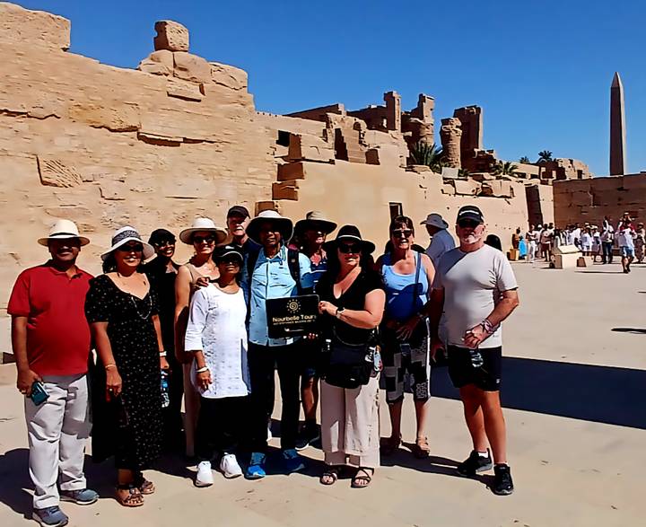 Groupe de touristes debout devant des ruines antiques.