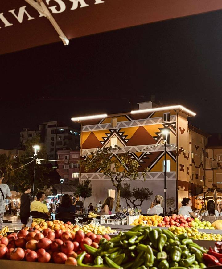 Bâtiment avec une fresque géométrique colorée illuminée la nuit.