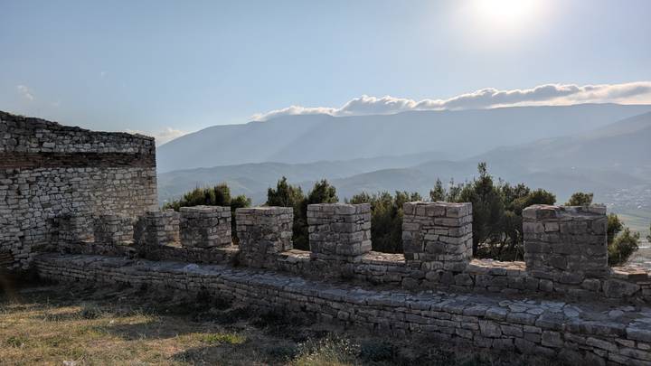 Mur de pierre historique avec vue panoramique sur les montagnes en arrière-plan.