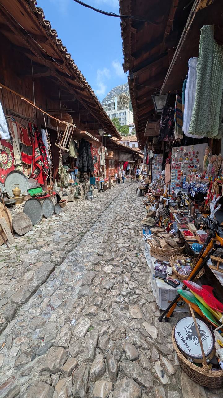 Rue pavée étroite bordée d'étals de marché traditionnels.