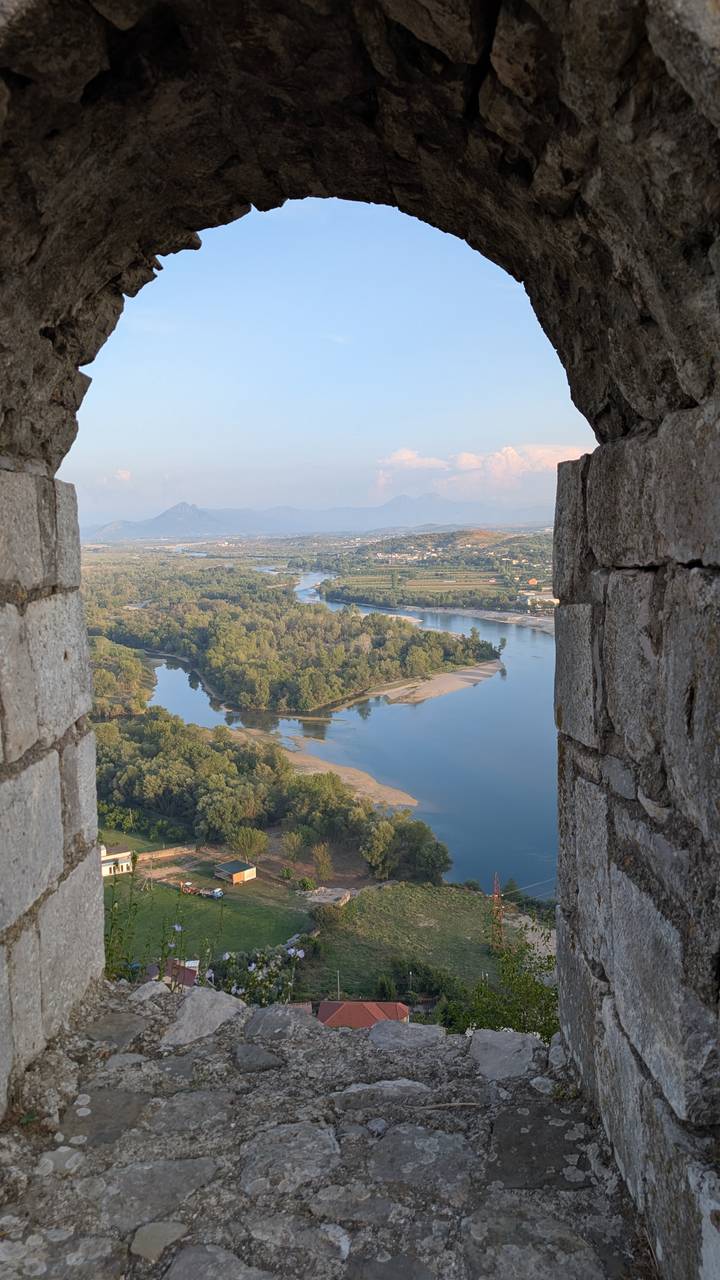 Vue panoramique d'une rivière avec une végétation luxuriante depuis une fenêtre de forteresse.