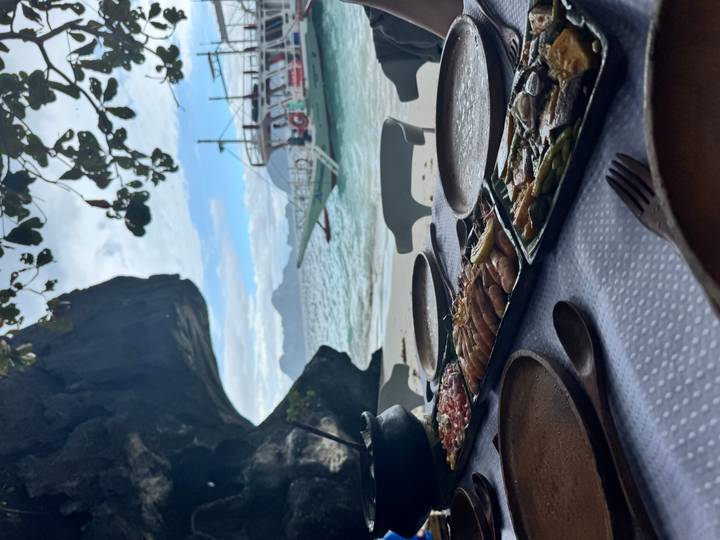 A table with seafood dishes overlooking the sea and a boat.