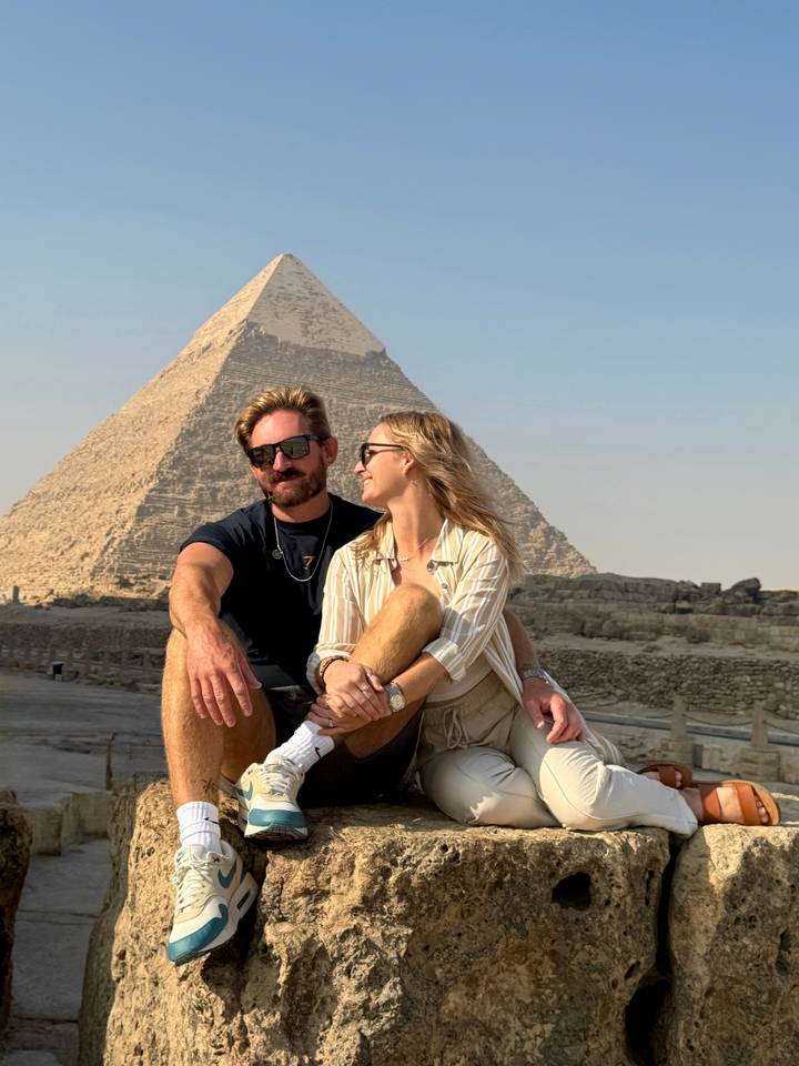 Couple posing in front of a pyramid.