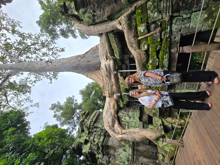 Deux femmes à des ruines couvertes de racines d'arbres.