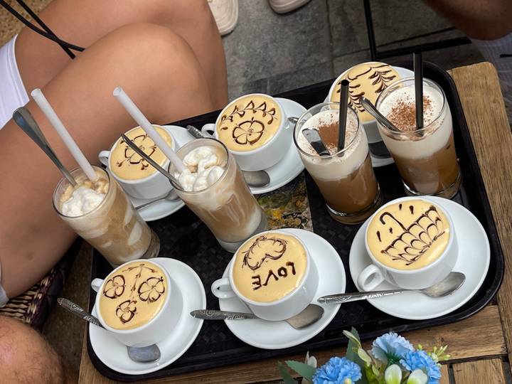 Multiple cups of coffee with artistic designs, placed on a tray.