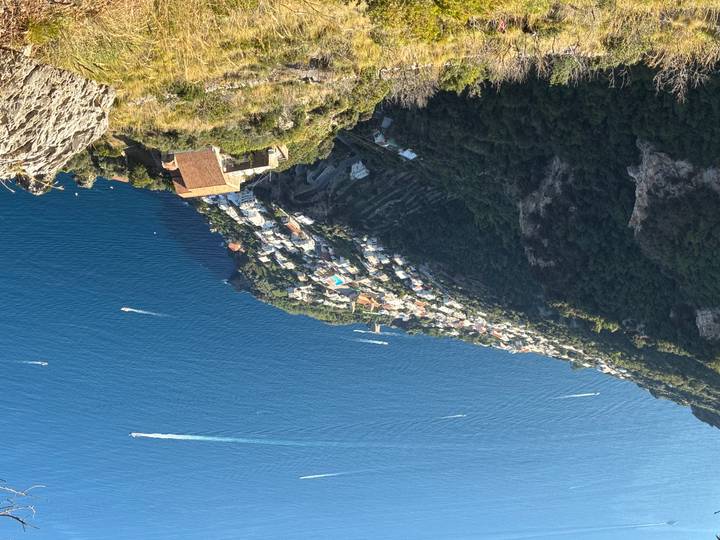 Mountainside town with houses and the sea in the distance.