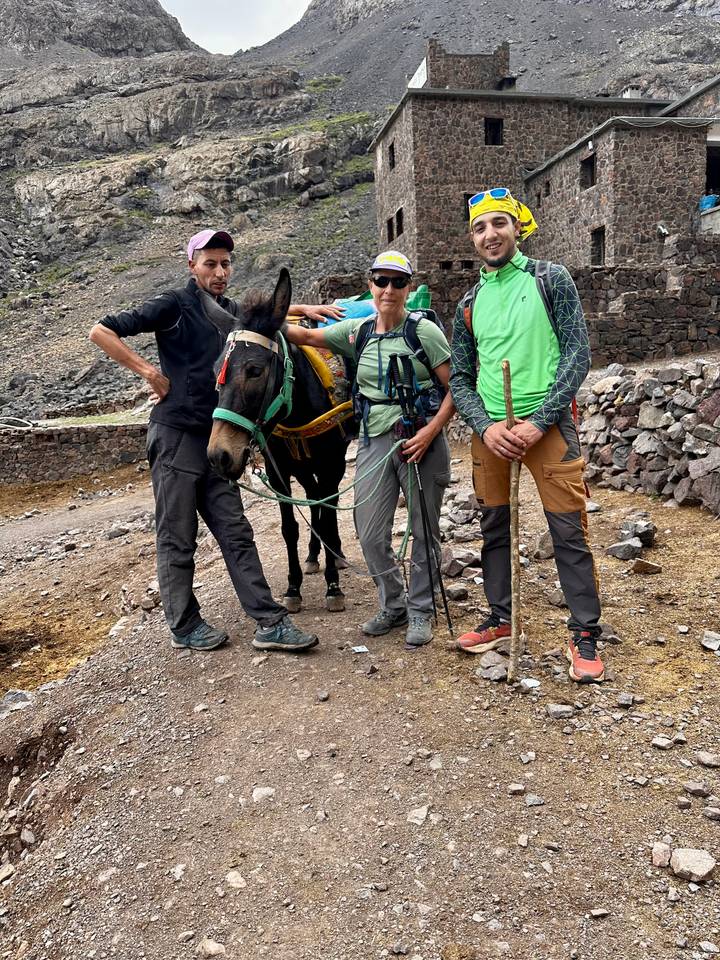 Trois personnes avec un âne sur un sentier de montagne.