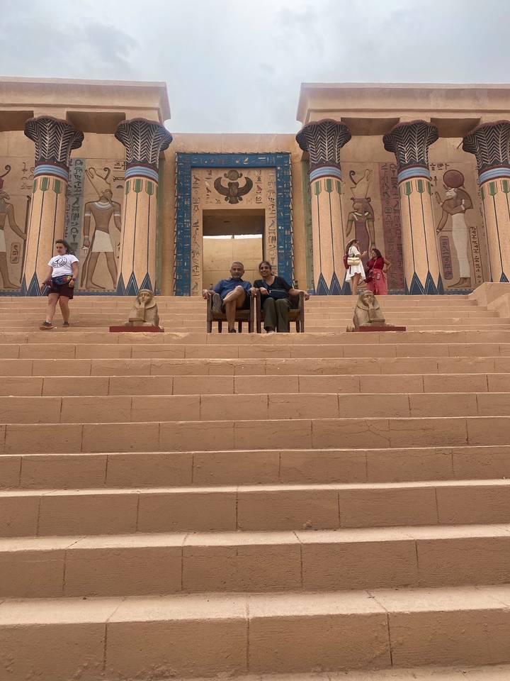 Des personnes assises sur des marches anciennes flanquées de statues de sphinx sur un site historique.