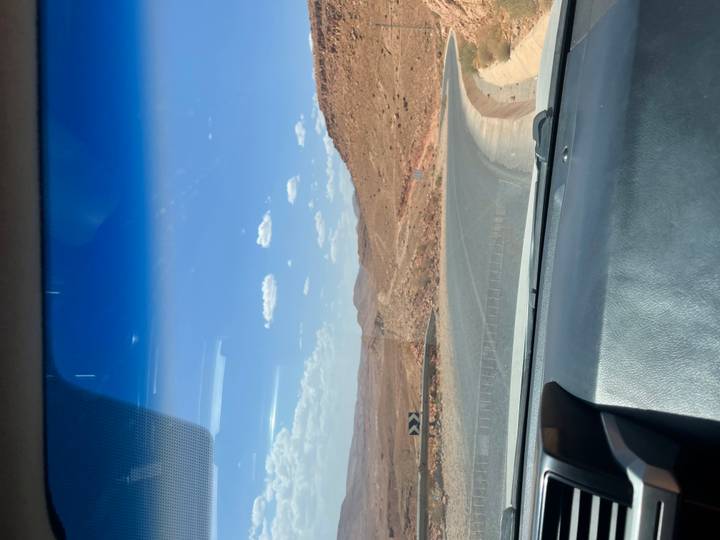 Vue depuis une voiture d'une route sinueuse traversant un paysage désertique aride.