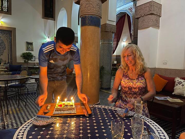 Femme avec un gâteau servie par un serveur dans un cadre chaleureux.