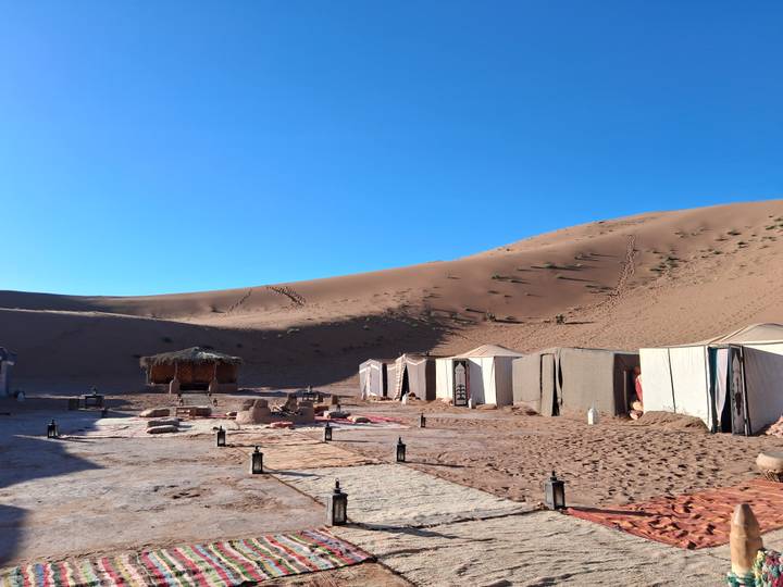 Campement dans le désert avec des tentes et une petite structure.